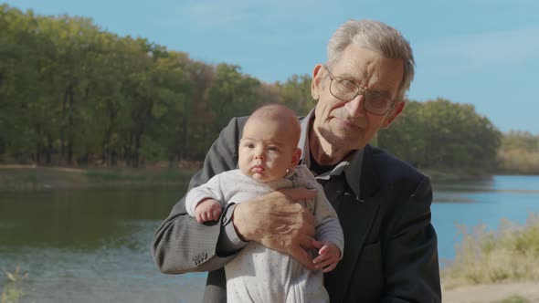 Senior Elderly Man Holding To His Baby Granddouther, Holding Him Close Up, Side View alt