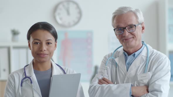 Positive Senior Doctor and Young Female Practitioner Posing for Camera alt
