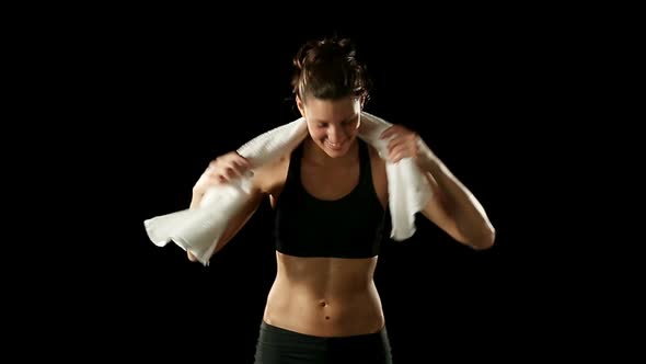 Young Athletic Woman Wearing Sporstwear is Drying with White Towel Isolated on Black