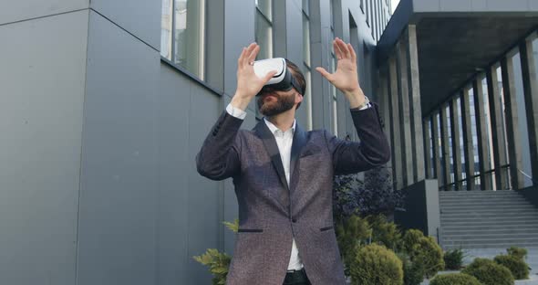 Businessman in Augmented Reality Goggles Working Outdoors Near Modern Urban Building alt