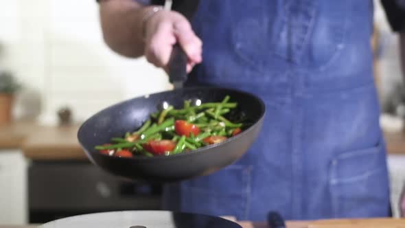 Chef roasts grilled vegetables in pan and effectively mixes tosses ingredients alt