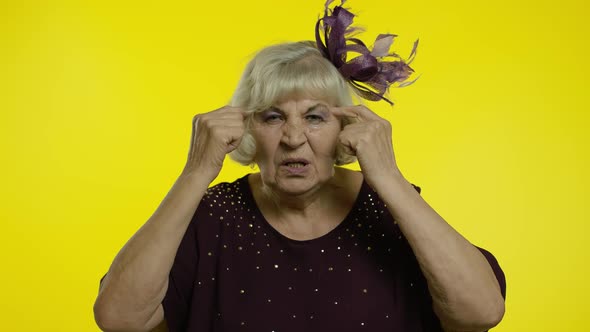 Displeased Annoyed Senior Old Woman Showing Stupid Gesture. Elderly Grandma on Yellow Background alt