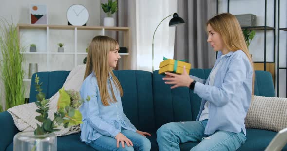Sister Giving Present Box to Her Younger Positive Sister and Embracing Her Congratulating  alt