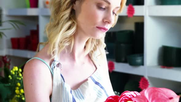 Female florist arranging flowers in flower shop alt