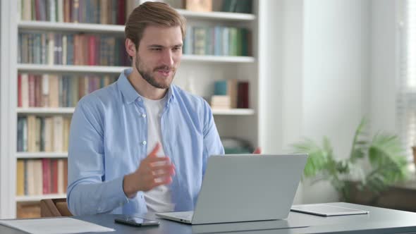 Man Talking on Video Call on Laptop in Office alt