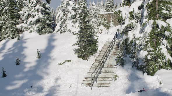 Snowboarder Doing A Trick On A Hand Rail In The Snow Covered Forest Terrain alt