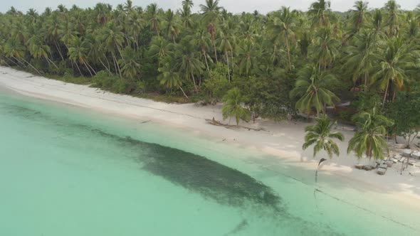 Aerial: woman relaxing on white sand beach turquoise water tropical alt