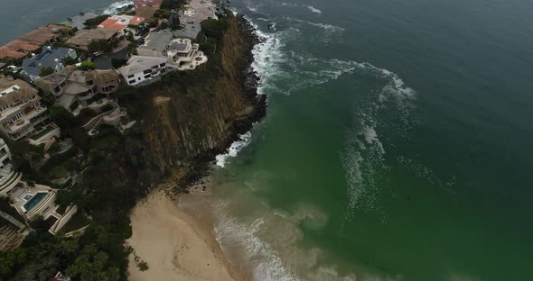 Aerial overhead shot of beach and pans up to reveal tall cliff and ocean alt