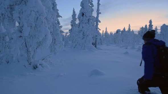 A Man With A Backpack Walking Along The Knee Deep Snow In The Region Of Lapland. -wide shot alt