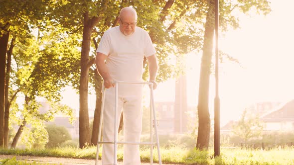 Disabled old man is walking with a walker. Handicapped patient in the park. alt
