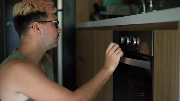 Male Cook Closed the Oven and Turn Buttons on