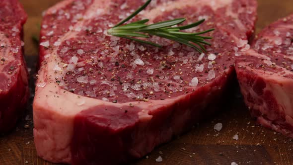 Seasoning raw ribeye beef steaks with rosemary alt