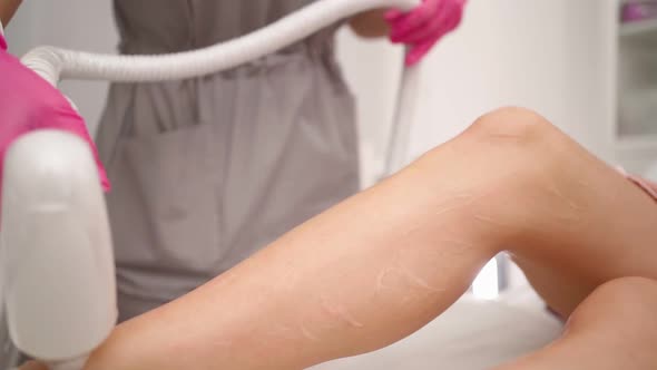 Beautician Doing Laser Hair Removal on Legs Woman Who is Lying on Medical Couch alt