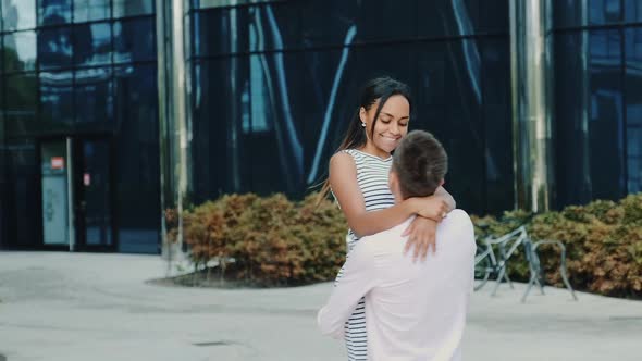 Happy Boyfriend Holding His Black Girlfriend in His Hands and Spinning Around Outdoors alt