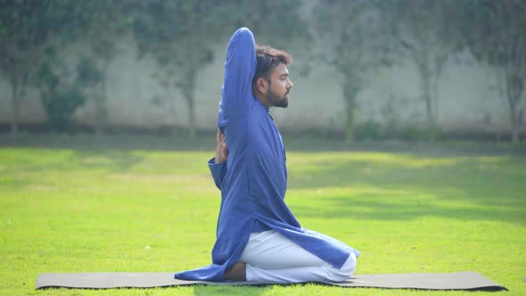 Indian man doing Gomukh asana or Cow Face Yoga Pose in an Indian traditional outfit Kurta Pajama alt