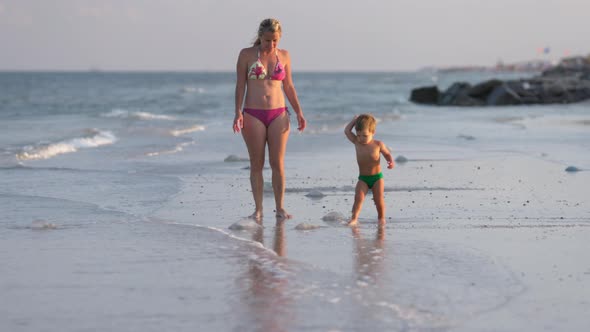 Mom Worries About Her Son and Tells Him About Poisonous Jellyfish Walking Along the Beach Strewn alt