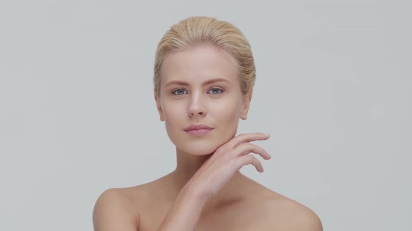 Studio portrait of young, beautiful and natural blond woman applying skin care cream. F alt