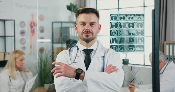 Doctor in Uniform Standing in front of Camera with Crossed Arms in Modern Medical Lab alt