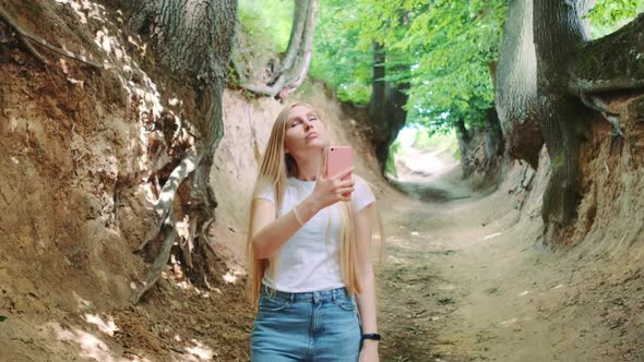 Blonde Young Woman Making Photos on Smartphone in Magical Roots Gorge alt