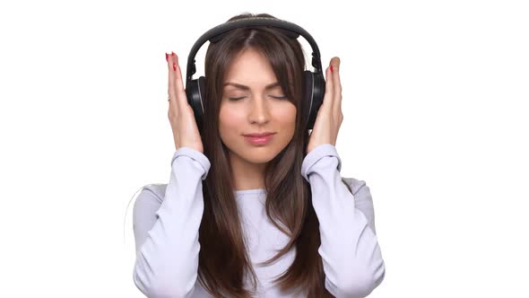 Smiling Beautiful Caucasian Female Listeting Music with Closed Eyes Using Headphones Over White alt