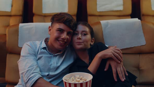 young caucasian couple kissing romantic moment while watching film in movie theater.