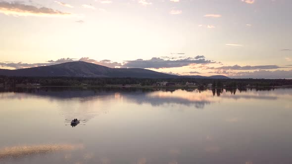 Group of friends rowing a boat in a calm lake during midnight sun in Lapland. alt