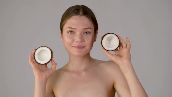Young beautiful girl holding coconut smiling and enjoying natural skin care alt