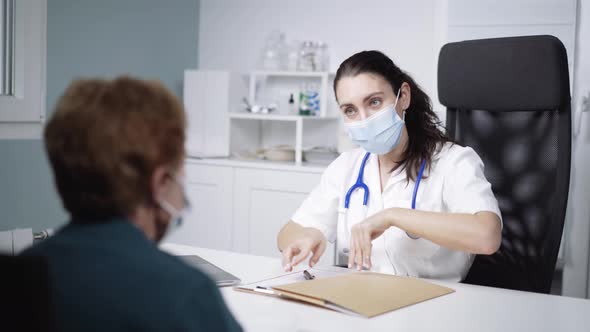 Physician sharing document and speaking with unrecognizable patient in clinic alt
