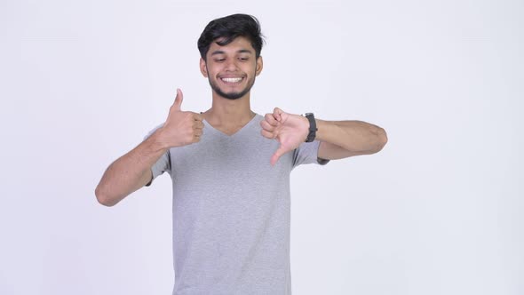 Young Bearded Indian Man Choosing Between Thumbs Up and Thumbs Down alt