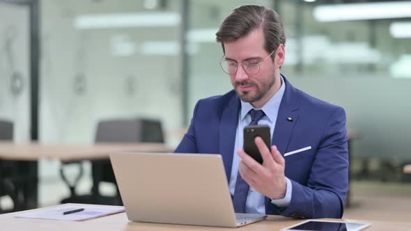 Professional Young Businessman Using Smartphone and Laptop  alt