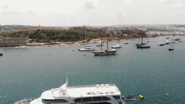 Fly over of harbour from the Tigné Seafront in Sliema city in Malta - Reveal aerial shot alt