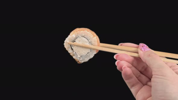 Female Hands Hold Japanese Chopsticks with Sushi Rolls on Transparent Background alt