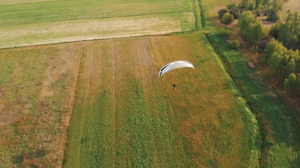 Aerial Of Paraglider Paragliding Over Green Fields alt