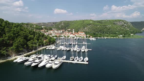 Aerial view of white sailboats and yachts embarked in a marina with turquoise, water. 