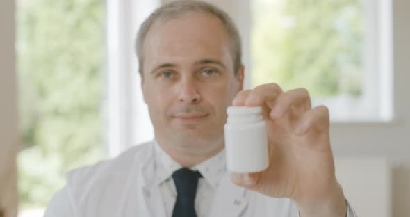 Rack Focus Changes From Face of Professional Physician To Jar with Medical Drugs, Close-up  alt