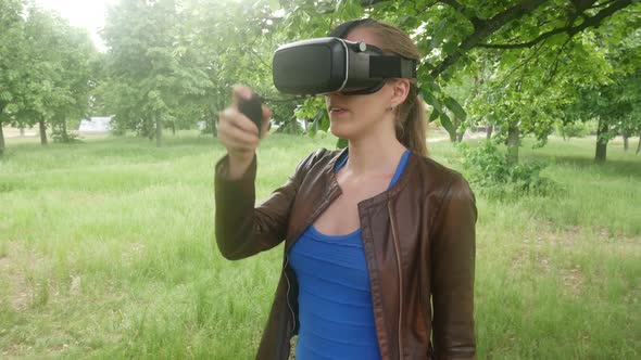 Sexy Woman In A Virtual Reality Helmet Uses A Virtual App In The Park alt