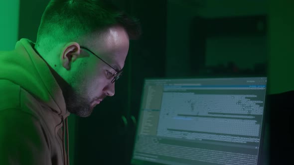 A Caucasian Man in Glasses Works on the Computer Types Checks the Information Coding Studying alt