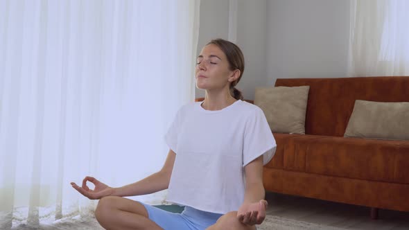 A Woman Does Meditation at Home in the Lotus Position