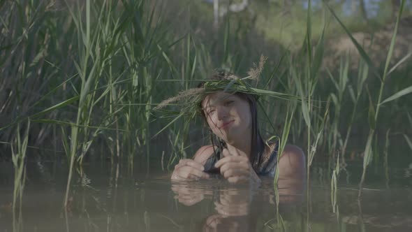 Beautiful Water Maiden with a Wreath on Her Head Smiling Comes Out of the Water alt