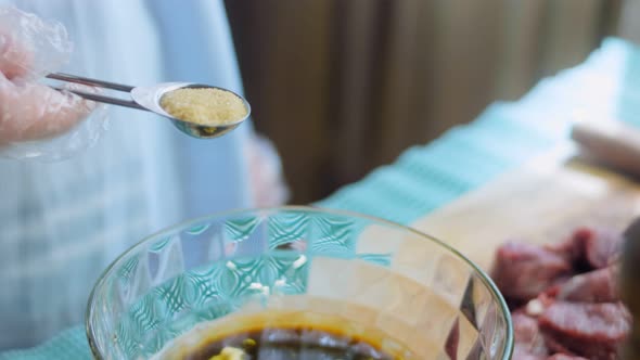 The Chef Adds a Tablespoon of Dijon Mustard to the Bowl with the Ingredients for the Marinade Sauce alt