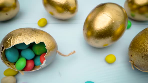 Golden Decorative Easter Eggs Filled with Colorful Candies on Wooden Table Close Up