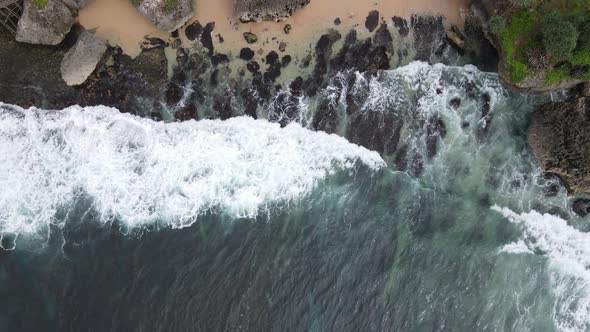 Top down aerial view of giant ocean waves crashing and foaming in coral beach alt