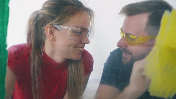 Man and Woman Paint Wall with Different Colors Smile Kissing alt