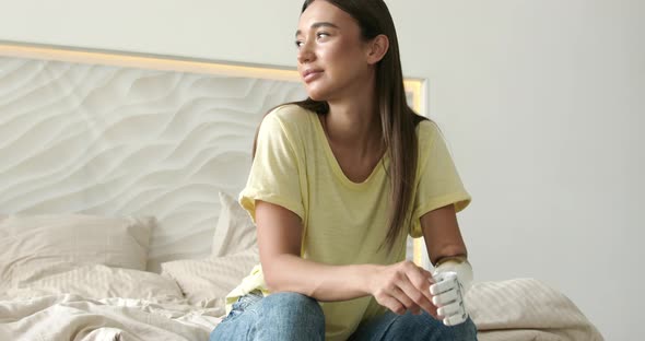 Portrait Smiling Happy Woman with Prosthetic Arm Sitting on Bed at Home Girl with Disability alt