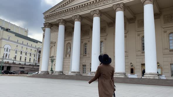 Elegant lady in hat and coat go to work, walk in Moscow center, Bolshoi Theater