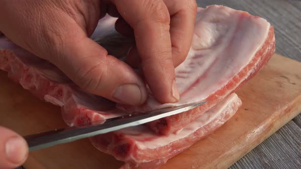 Closeup of the Male Hands Cutting Off the Fatty Film From the Raw Ribs alt