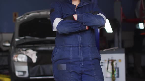 Portrait of female mechanic with arms crossed smiling at a car service station alt