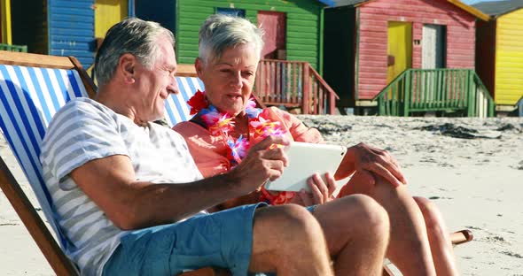Senior couple interacting with each other while using digital tablet alt