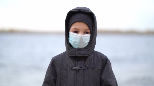Boy Medical Mask on His Face During Quarantine Stands on Beach During the Second Wave Quarantine alt