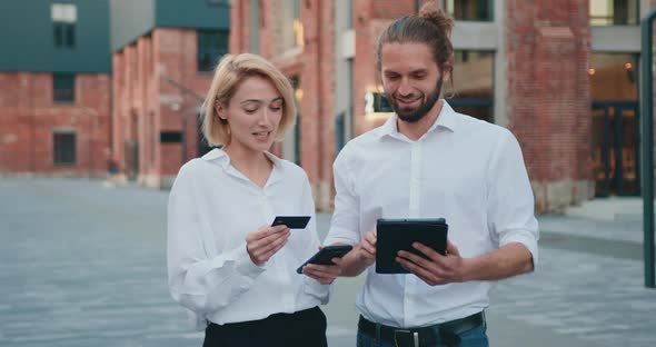 Caucasian Business Partners with Bank Credit Card and Didgital Table Outdoors. alt